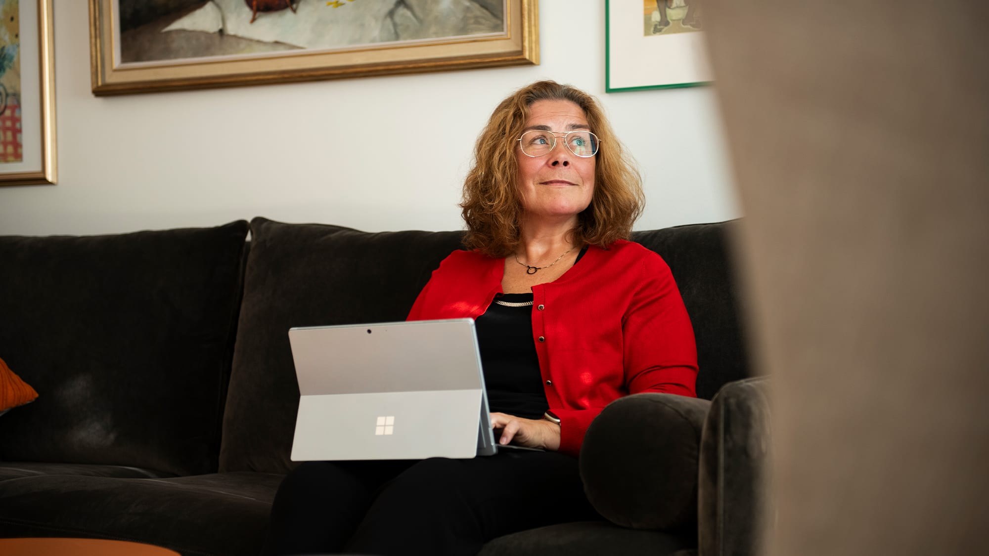 Mia sitter med datorn i knät i soffan