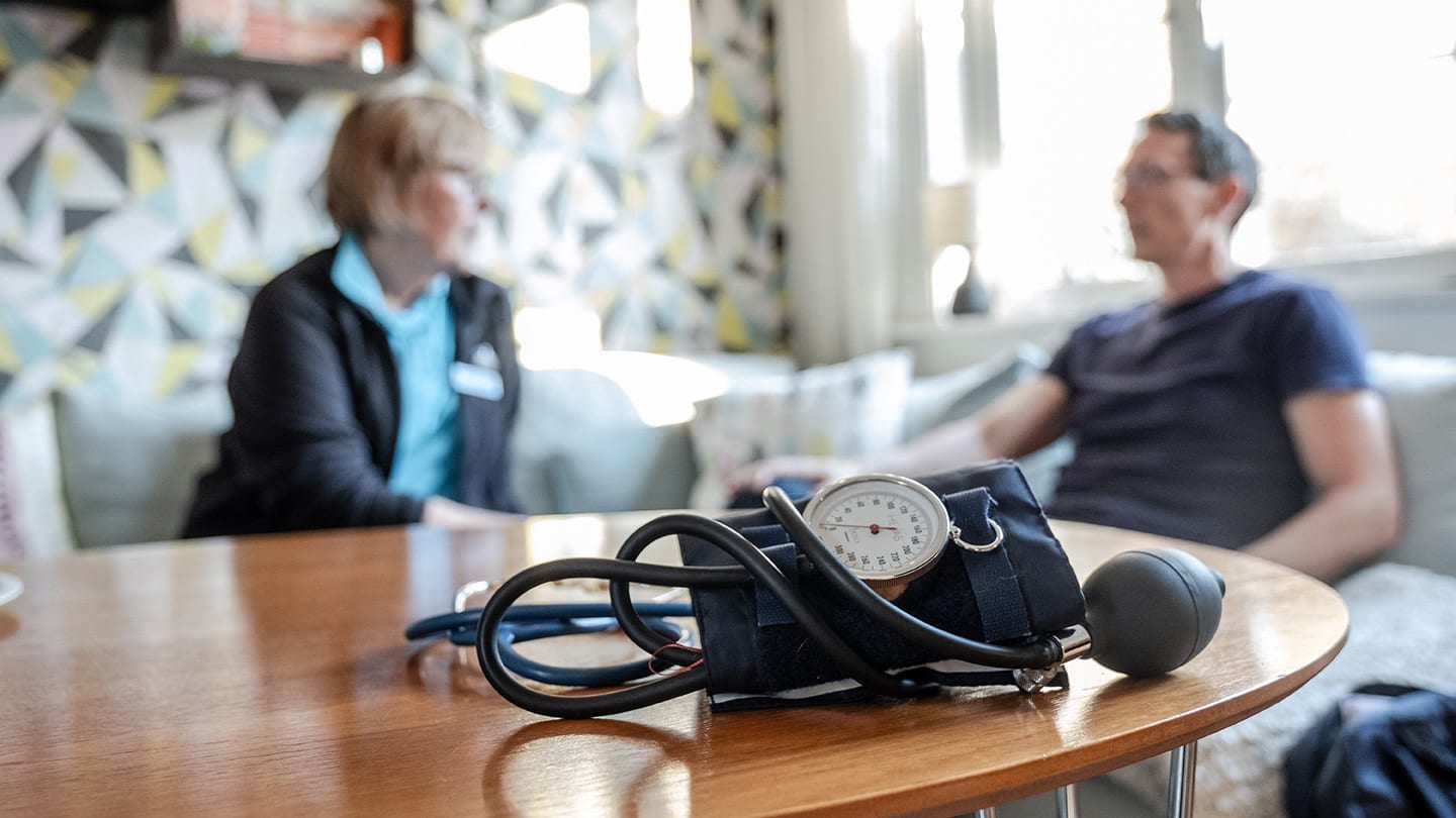 Sjuksköterska och patient sitter i hemmiljö