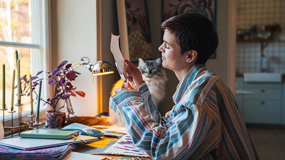 kvinna vid ett skrivbord fullt av skisser, målningar och anteckningsböcker