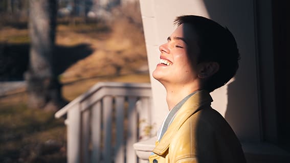 kvinna halvt i skugga som skrattar mot solen