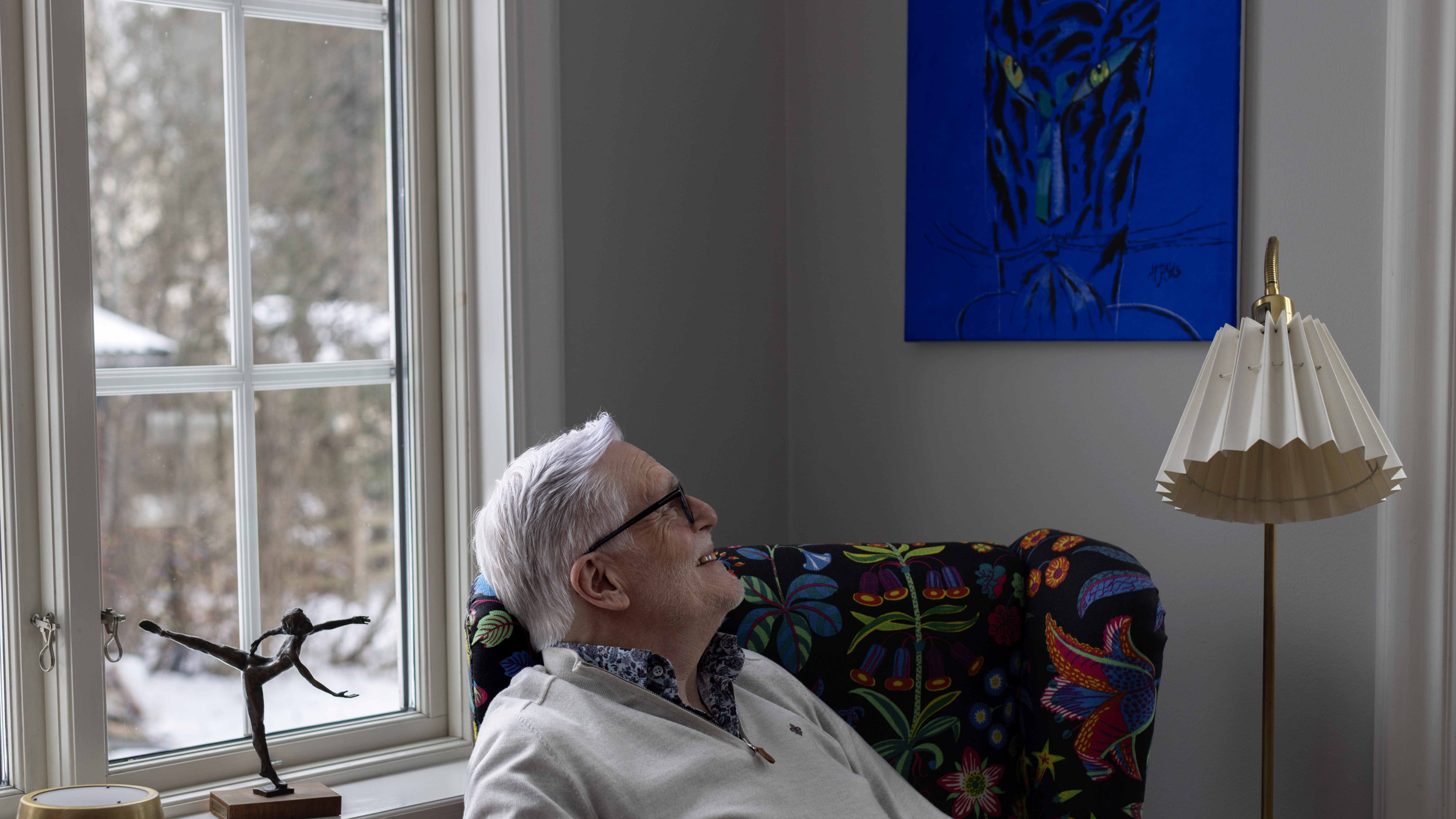 Ole blickar upp mot en tavla med en blå katt som hänger på hans vägg. Foto: Sanna Percivall.