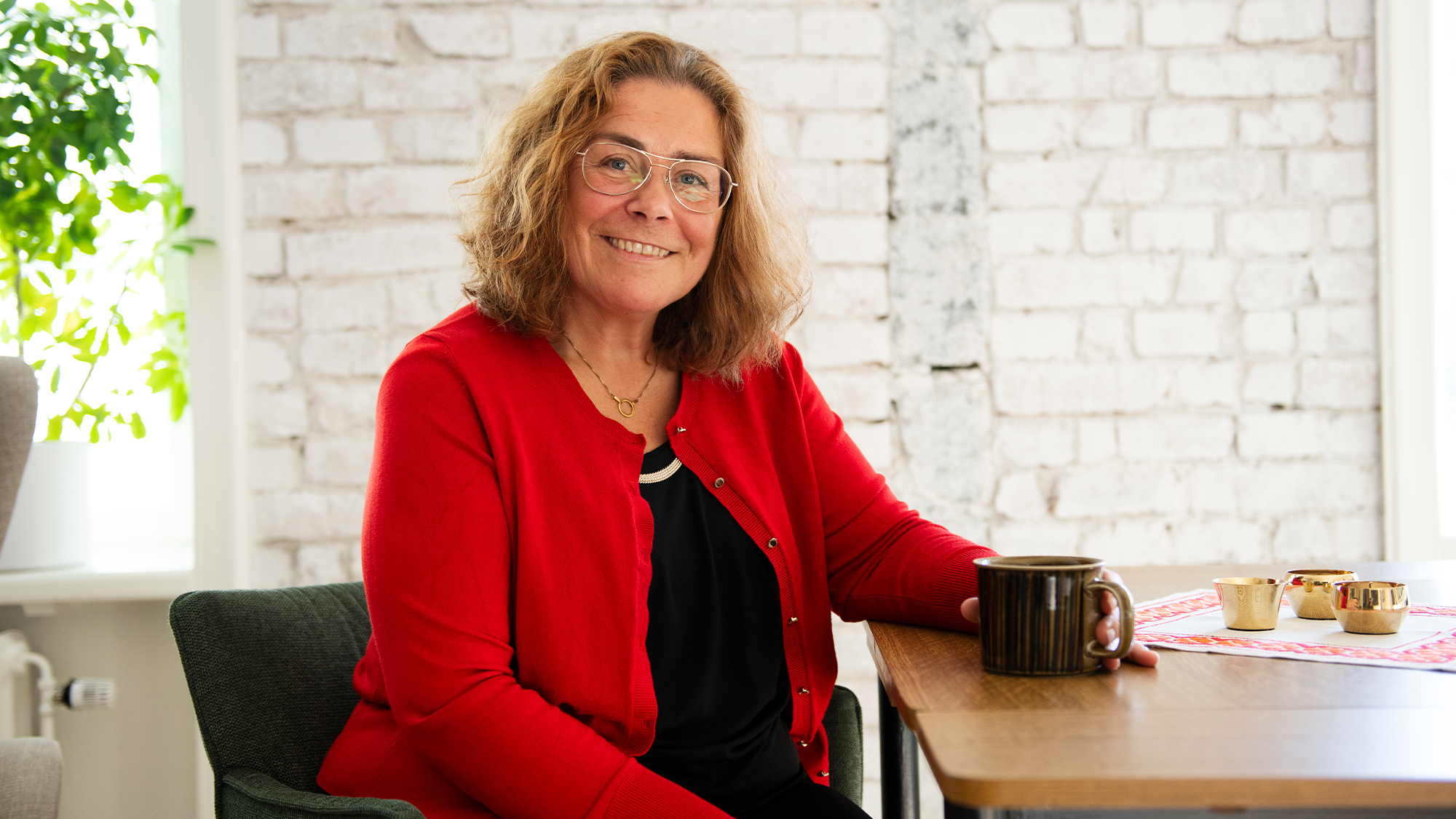 Mia sitter vid sitt köksbord med en kopp kaffe