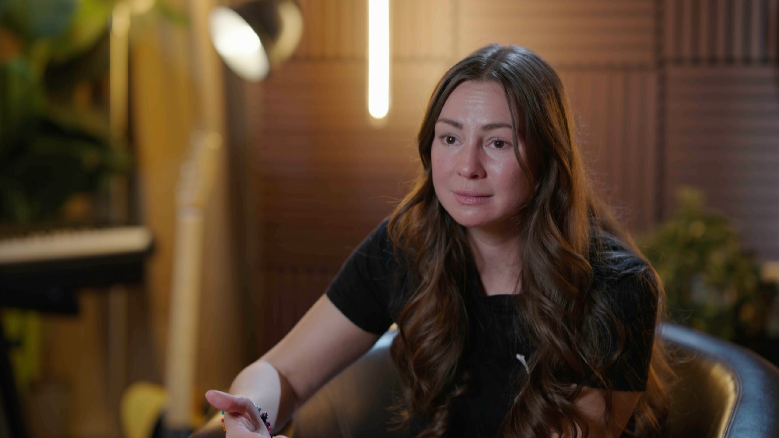 Kvinna i brunt långt hår och svart t-shirt intervjuas. 